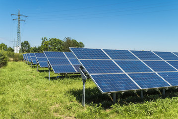 Stromtrasse und Solaranlage auf grüner Wiese