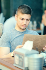 Man in outdoor restaurant looking at the menu