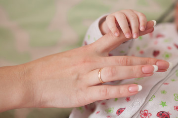 Son and mother, baby holding moms finger. Family concept