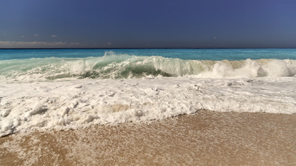 Wave spray splash over beach at blue sea