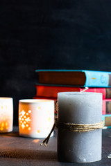 Candle and books on a black wooden background, selective focus