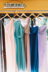 Beautiful pastel dresses hang on the pegs under lettering 'Beach