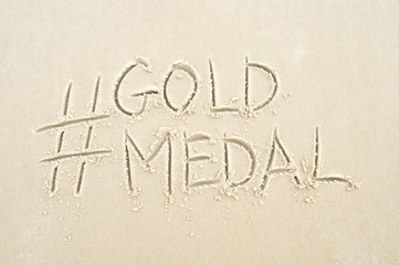 Hashtag social media message for gold medal written in sand on the beach in Rio de Janeiro, Brazil