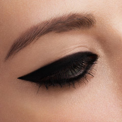 Cosmetics & make-up. Beautiful female eye with sexy black liner makeup. Fashion big arrow shape on woman's eyelid. Chic evening make-up