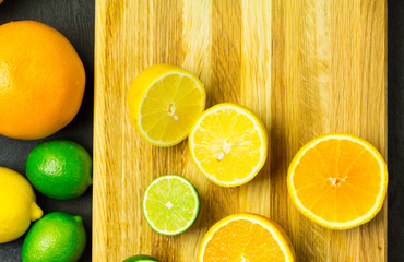 Fototapeta na wymiar Halves citrus fruit on a cutting board on black wooden background