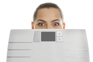 Beautiful young woman hiding behind scales on white background