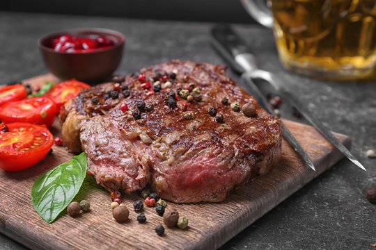 Tasty steak with tomatoes and spices on cutting board