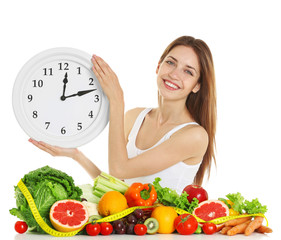 Woman with clock and healthy food on white background