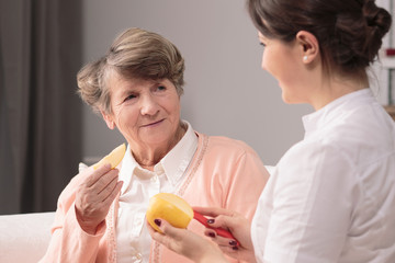 Elderly womana and female caregiver eating an apple