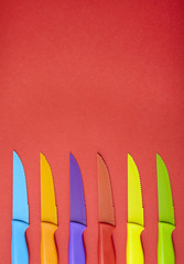 Colorful steak knives arranged on a red background forming a page footer