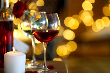 Romantic composition with wine and candle on blurred background