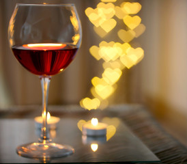 Glass of red wine on blurred romantic background