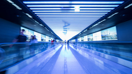 People going in walkway and riding flat escalators at the airport of Seoul, South Korea. Futuristic blue toned shot