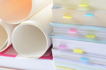 Documents with paper notes and roll of white papers on desk,office supplies.