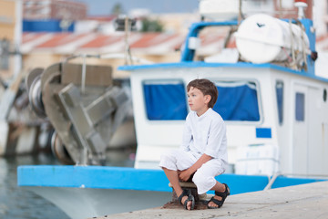 Thoughtful boy looks at ship at sea and dreams