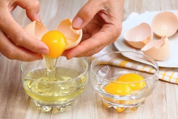 Woman hands breaking an egg to separate  egg- white &  yolks - obrazy, fototapety, plakaty