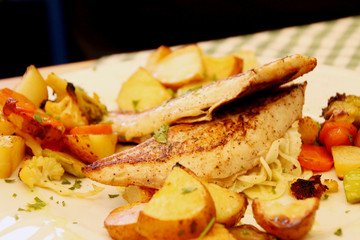 Bass fillets with potatoes and vegetables.