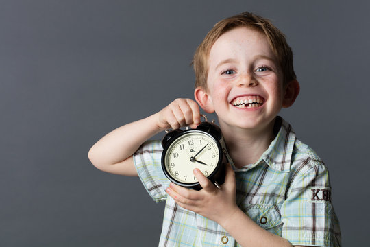 laughing little kid with missing tooth holding clock for time