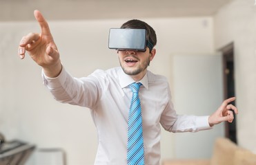 Happy and excited businessman is wearing virtual reality headset and is touching something.