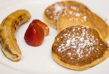 Pancakes with powdered baked banana and strawberries