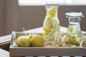Jugs of lemon water and lemons on an wooden tray