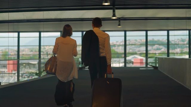 Couple in formal wear walking in airport with bags, business trip, partners