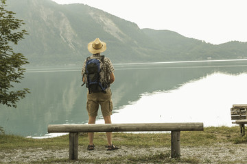 Ein Mann mit Strohhut schaut über den See und genießt die Aussicht. 