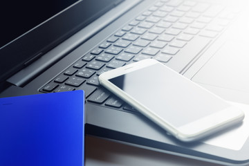 White smartphones on black laptop computer or notebook keyboard with blue external hardisk