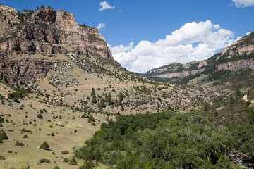 A road going through the mountains in Wyoming on a clear day.