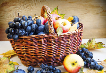 Organic autumn fruits in basket with dried leaves