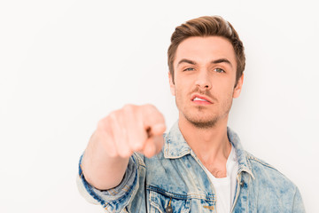Angry young man in jeans jacket pointing his fingers on camera