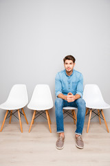 Young handsome man sitting on chair and waiting for his turn