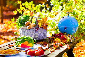 Grill and picnic basket in autumn garden