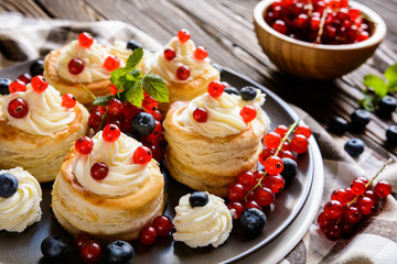 Puff pastry cakes filled with whipped cream and berries