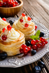 Puff pastry cakes filled with whipped cream and berries