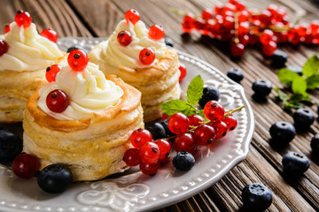 Puff pastry cakes filled with whipped cream and berries