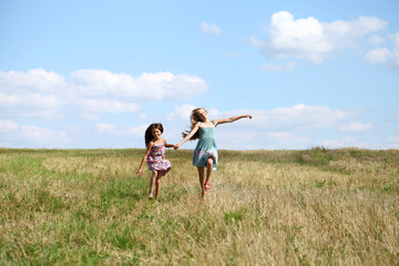 Fototapeta na wymiar Two little girls running in summer field