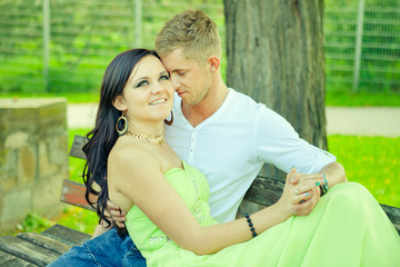 Fototapeta premium Attractive the guy with the girl sit and embrace on a bench