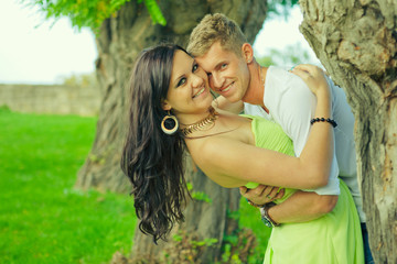 Naklejka premium Happy guy with the girl look out because of a tree
