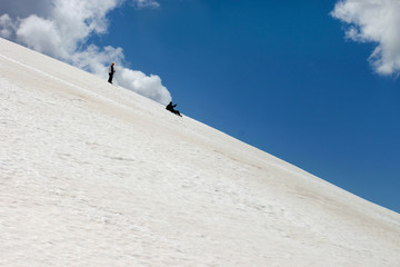 Couple sliding downhill the snow mountain and having fun