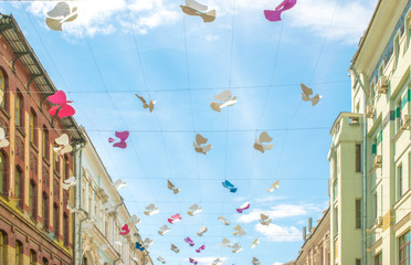 Fototapeta na wymiar Street decorated with colored paper bird against sky