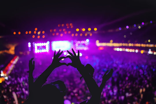 heart shaped hands showing love at festival. Silhouette against concert Lights background
