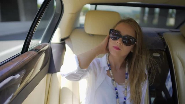 Pretty blonde woman enjoying trip on backseat of expensive auto, tourism