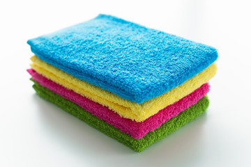 Obraz na płótnie Canvas colourful, stacked bathroom towels in blue, yellow, pink and green colours, isolated on a white background, close up
