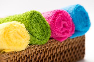 rolled, colorful bathroom towels in a wicker basket. isolated on a white background, horizontal