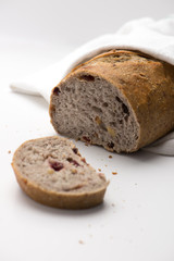 whole grain bread with dry cranberry and walnut. sliced and wrapped in a white kitchen cloth. isolated on a white background