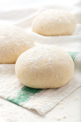 Fototapeta na wymiar fresh, handmade, uncooked pizza or bread dough balls on a kitchen cloth
