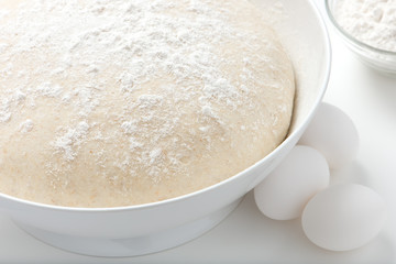 fresh, handmade, uncooked pizza or bread dough in a white bowl with fresh, white, organic eggs and white flour. close up, horizontal