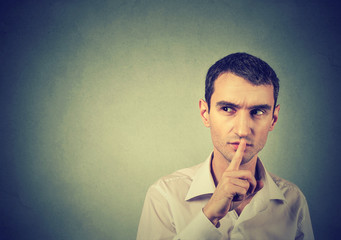 Suspicious man giving Shhhh quiet, silence, secret gesture