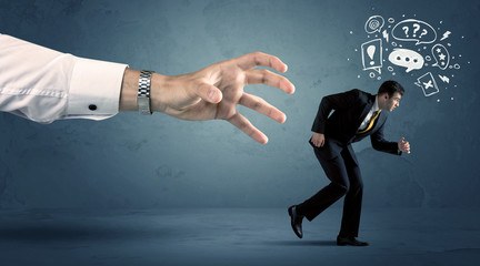 Fototapeta premium Business man running from a big hand